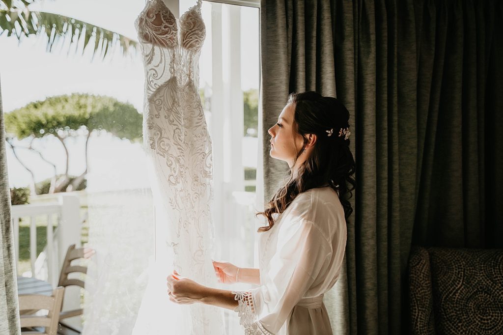 Bride looking at hung up wedding dress Hawks Cay Resort Wedding Photography captured by South Florida Wedding Photographer Krystal Capone Photography 