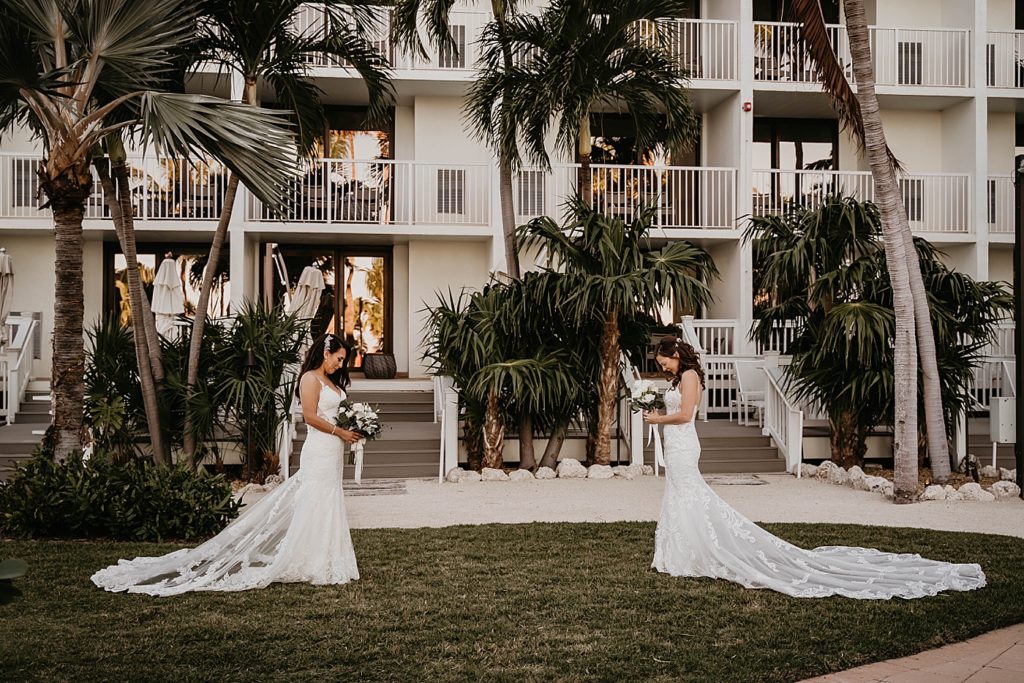 Brides first look standing across each other holding white bouquets LGBTQIA+ Hawks Cay Resort Wedding Photography captured by South Florida Wedding Photographer Krystal Capone Photography 