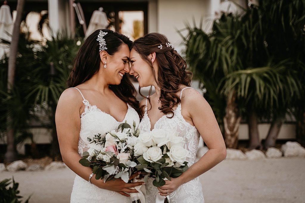 Brides nuzzling foreheads against each other holding bouquets LGBTQIA+ Hawks Cay Resort Wedding Photography captured by South Florida Wedding Photographer Krystal Capone Photography 