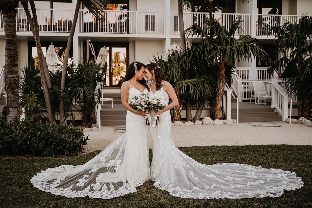 Brides with their foreheads against each other after First Look holding white bouquets LGBTQIA+ Hawks Cay Resort Wedding Photography captured by South Florida Wedding Photographer Krystal Capone Photography 