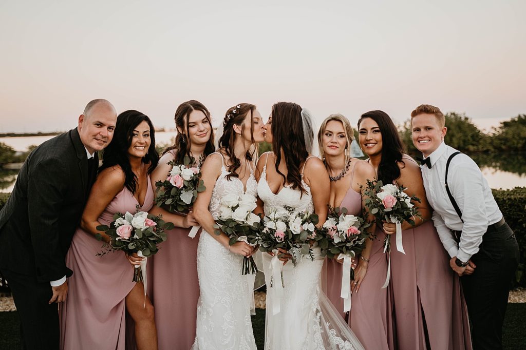 Brides kissing with Wedding party gather close around them Hawks Cay Resort Wedding Photography captured by South Florida Wedding Photographer Krystal Capone Photography
