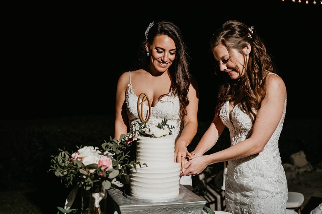 Brides cutting cake together at Nighttime Reception Hawks Cay Resort Wedding Photography captured by South Florida Wedding Photographer Krystal Capone Photography