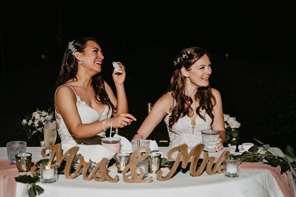 Brides laughing at sweetheart table with "Mrs & Mrs" decor Hawks Cay Resort Wedding Photography captured by South Florida Wedding Photographer Krystal Capone Photography