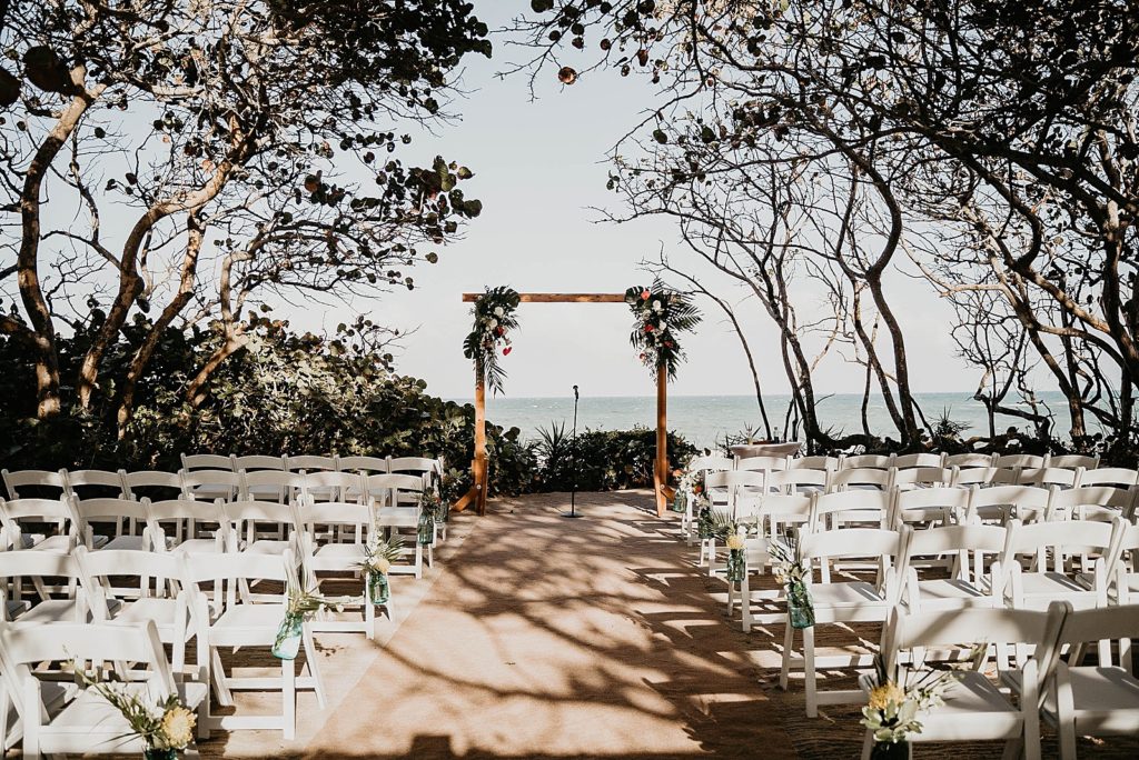 Before Ceremony Detail shot of wood arch and white folding chairs right by the waterfront Jupiter Beach Resort Wedding Photography captured by South Florida Wedding Photographer Krystal Capone Photography 