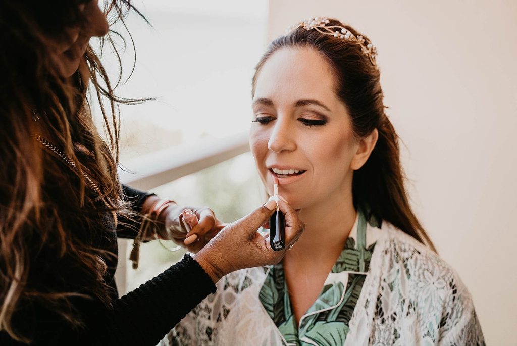 Bride getting ready with makeup artist doing lipstick Jupiter Beach Resort Wedding Photography captured by South Florida Wedding Photographer Krystal Capone Photography 