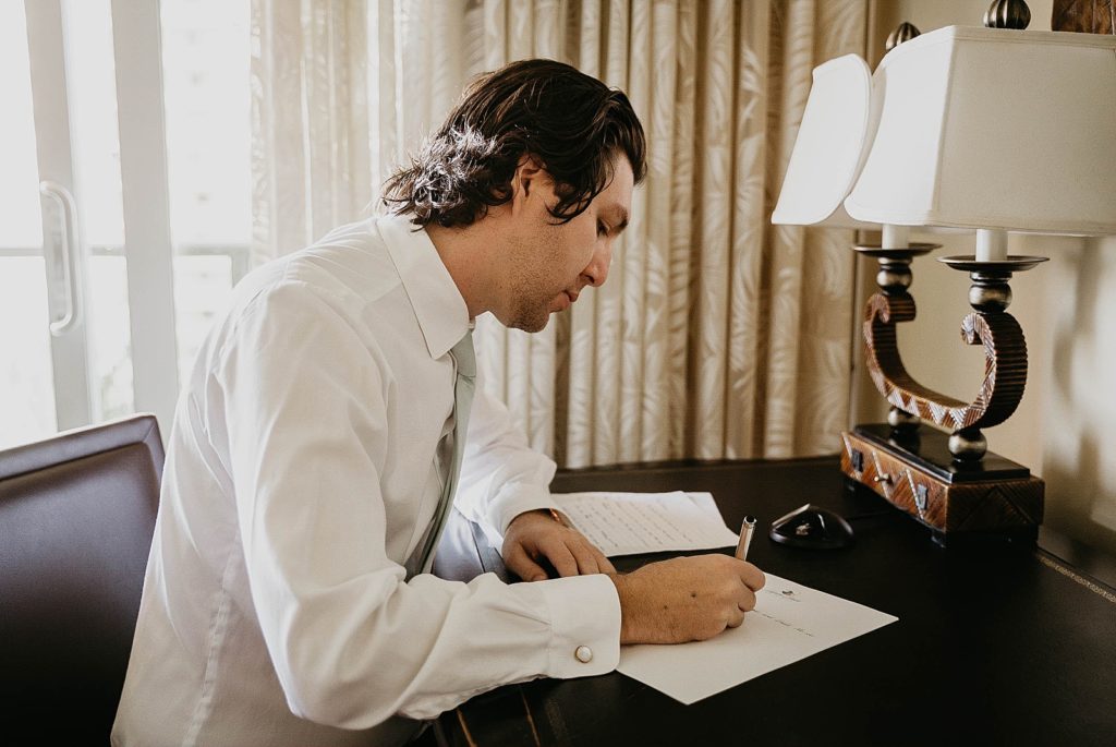 Groom writing letter to Bride on table getting ready Jupiter Beach Resort Wedding Photography captured by South Florida Wedding Photographer Krystal Capone Photography 