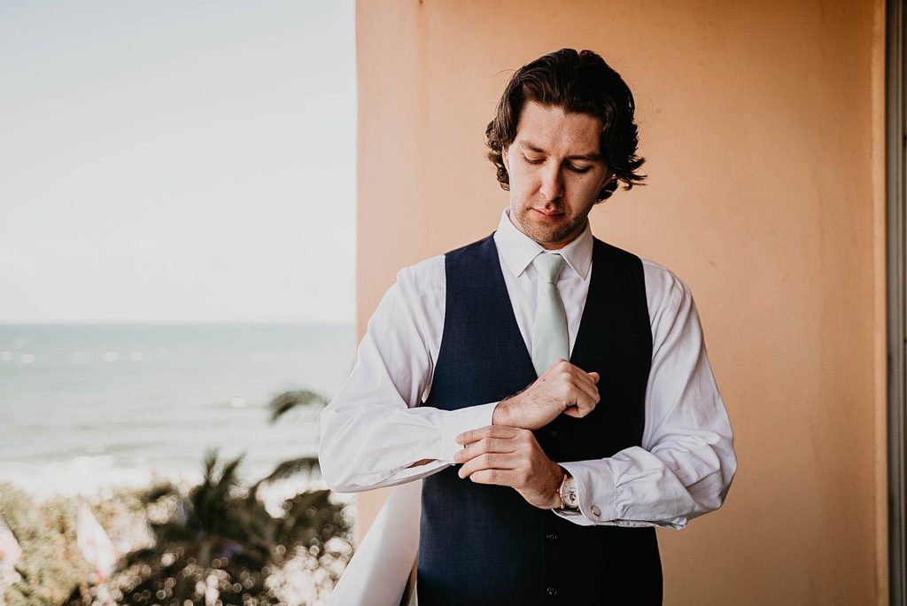 Groom adjusting cuff with the ocean in the distance Jupiter Beach Resort Wedding Photography captured by South Florida Wedding Photographer Krystal Capone Photography 