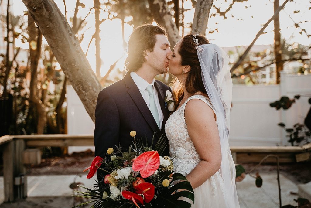 Bride and Groom kissing with beautiful tropical bouquet Jupiter Beach Resort Wedding Photography captured by South Florida Wedding Photographer Krystal Capone Photography 