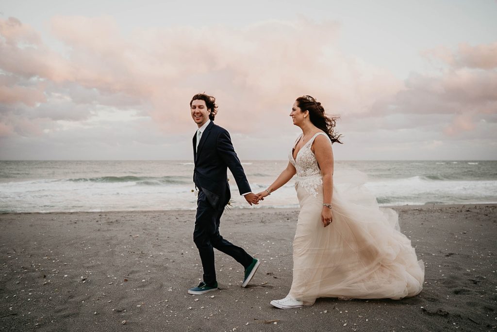 Groom holding Bride's hand and leading her on walk on the beach Jupiter Beach Resort Wedding Photography captured by South Florida Wedding Photographer Krystal Capone Photography 