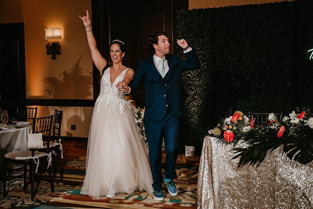Bride and Groom holding hands and putting their hands in the air entering Reception Jupiter Beach Resort Wedding Photography captured by South Florida Wedding Photographer Krystal Capone Photography 