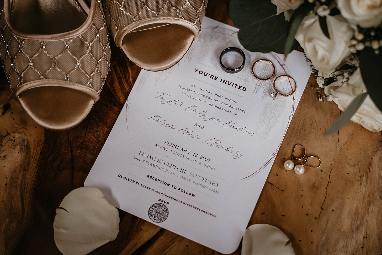 Wedding detail shot of shoes wedding bands engagement ring invitation and pearl earrings on wood backdrop Living Sculptures Sanctuary Wedding Photography captured by South Florida Wedding Photographer Krystal Capone Photography 