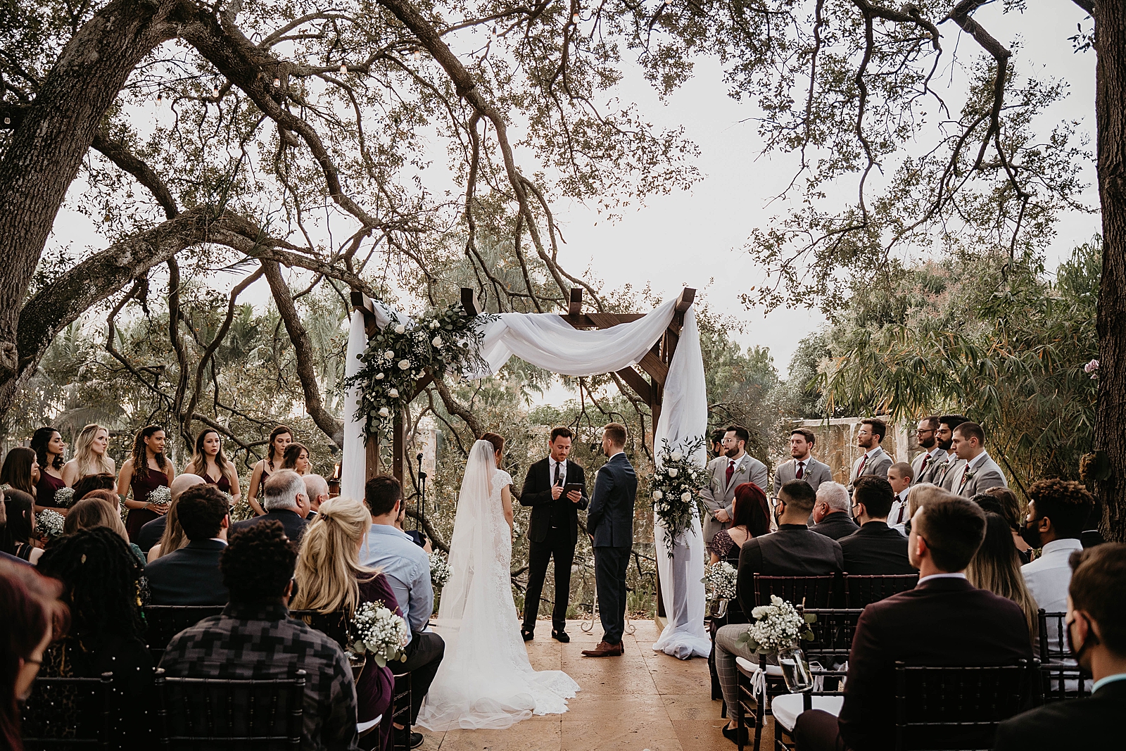 Wide shot of Bride and Groom at the alter listening to the Homily with full Bridal party Living Sculptures Sanctuary Wedding Photography captured by South Florida Wedding Photographer Krystal Capone Photography 