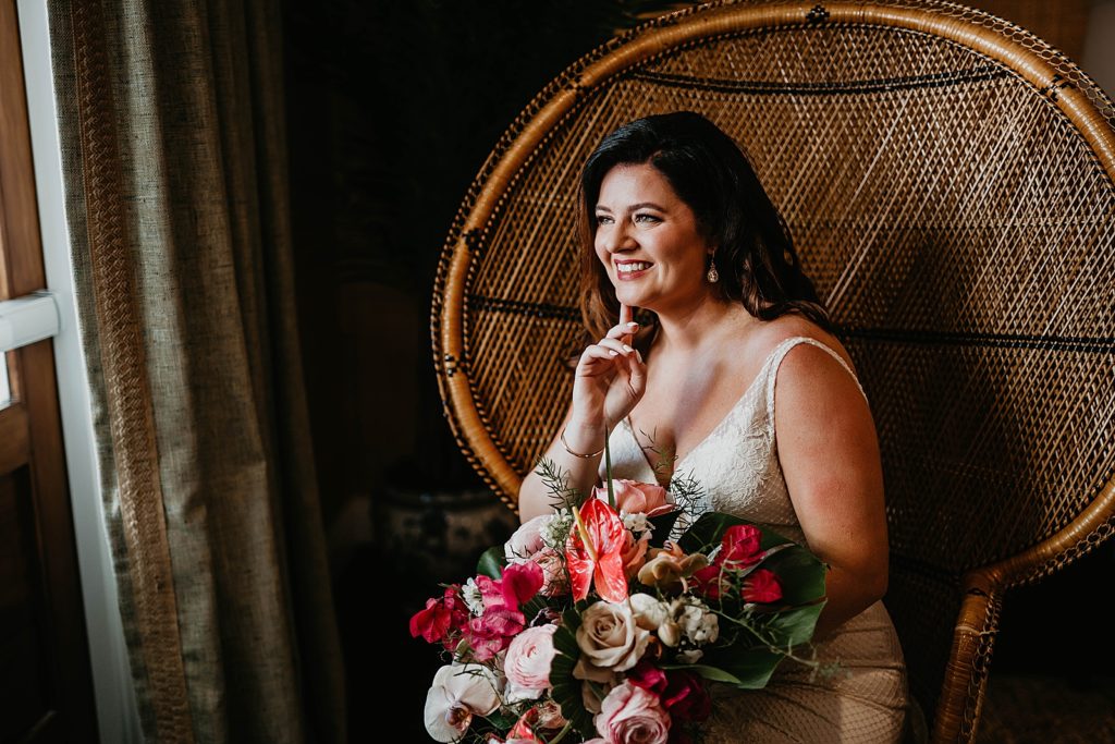 Bride smiling sitting down with red bouquet Pelican Club Wedding Photography captured by South Florida Wedding Photographer Krystal Capone Photography 