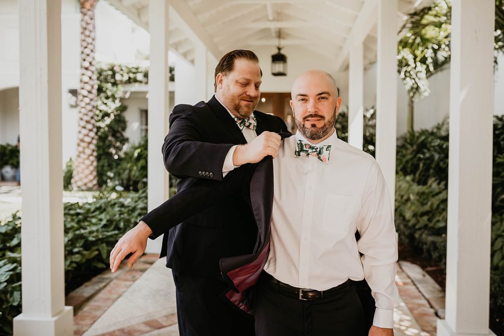 Groom getting help putting on jacket getting ready Pelican Club Wedding Photography captured by South Florida Wedding Photographer Krystal Capone Photography 