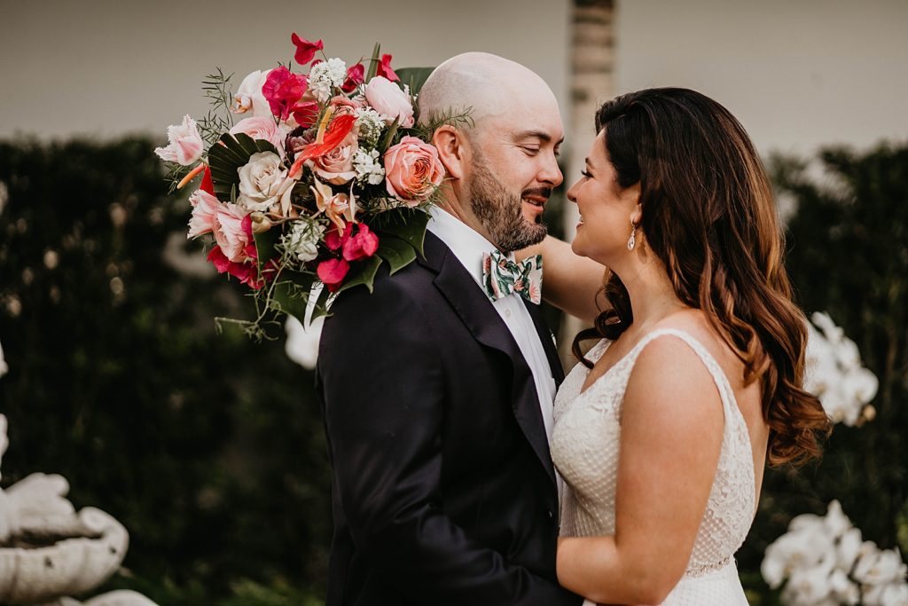 Bride and Groom holding each other with Bride holding bouquet behind Groom Pelican Club Wedding Photography captured by South Florida Wedding Photographer Krystal Capone Photography 