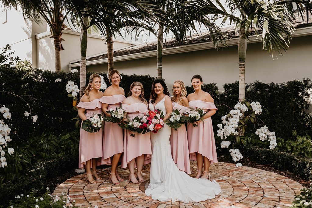 Bride and Bridesmaids standing with bouquets in hand Pelican Club Wedding Photography captured by South Florida Wedding Photographer Krystal Capone Photography 