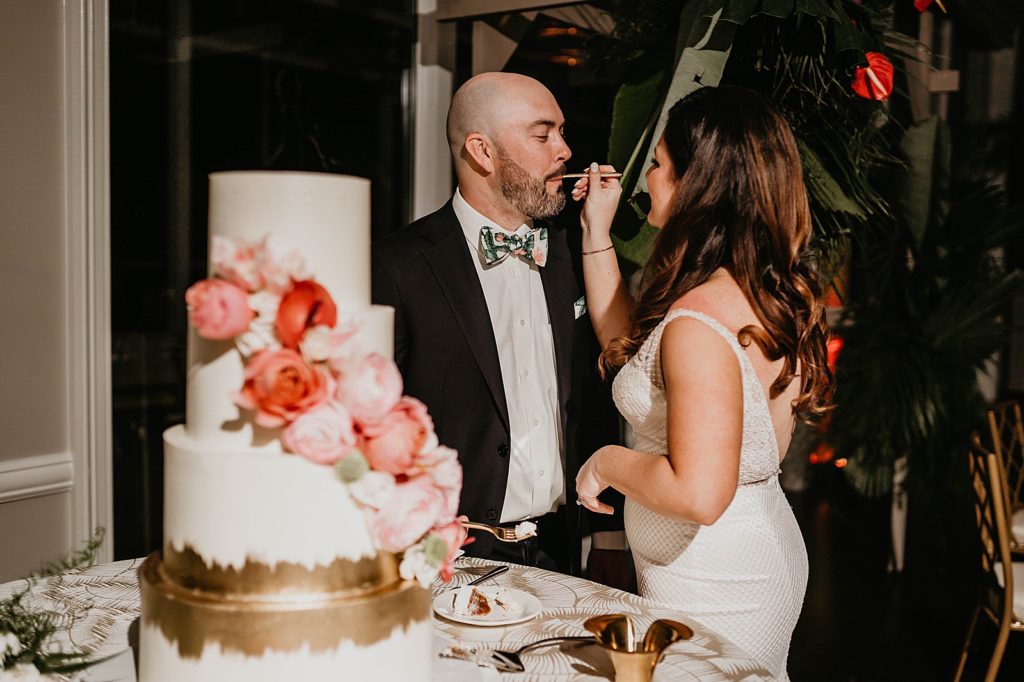 Bride giving Groom a bite of cake Reception Pelican Club Wedding Photography captured by South Florida Wedding Photographer Krystal Capone Photography 
