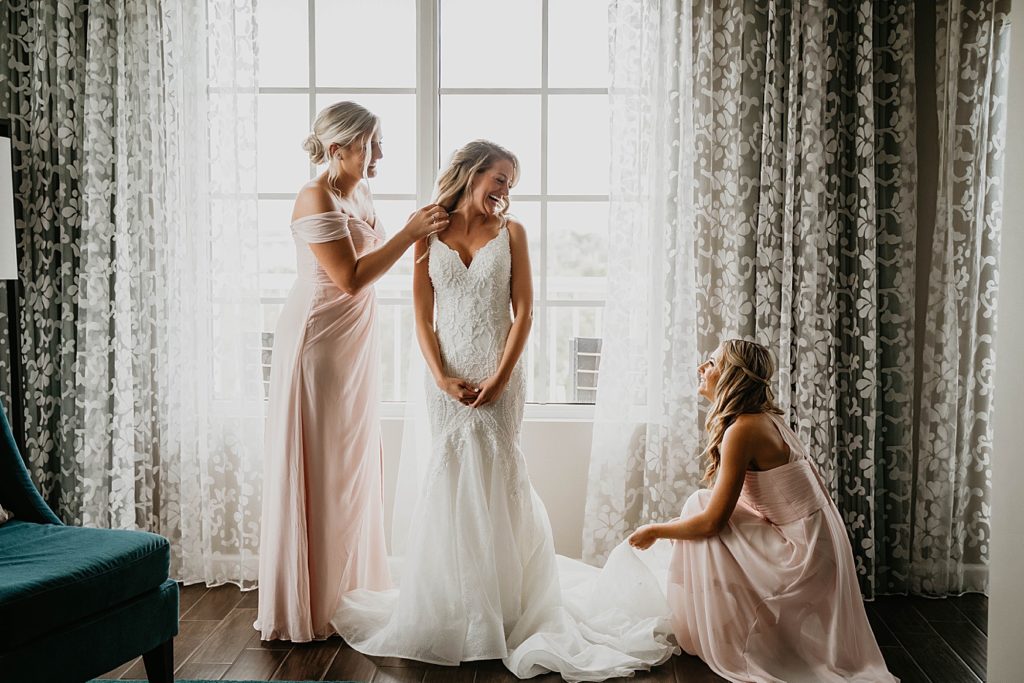 Bridesmaids assisting Bride with getting her dress on Pelican Club Wedding Photography captured by South Florida Wedding Photographer Krystal Capone Photography