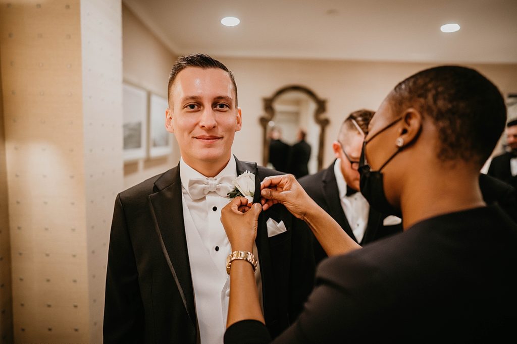 Groom getting ready putting on boutonniere Pelican Club Wedding Photography captured by South Florida Wedding Photographer Krystal Capone Photography 
