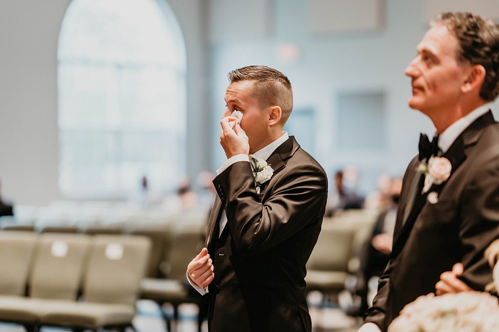 Groom wiping tears of joy seeing bride entering the ceremony Pelican Club Wedding Photography captured by South Florida Wedding Photographer Krystal Capone Photography