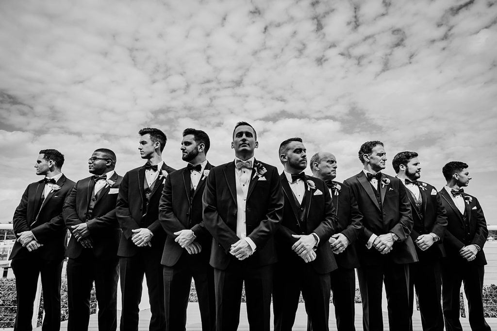B&W Groom and groomsmen standing with crossed hands standing in formation Pelican Club Wedding Photography captured by South Florida Wedding Photographer Krystal Capone Photography