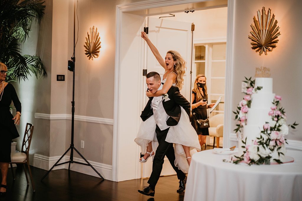 Bride piggy back entrance with Groom into Reception Pelican Club Wedding Photography captured by South Florida Wedding Photographer Krystal Capone Photography