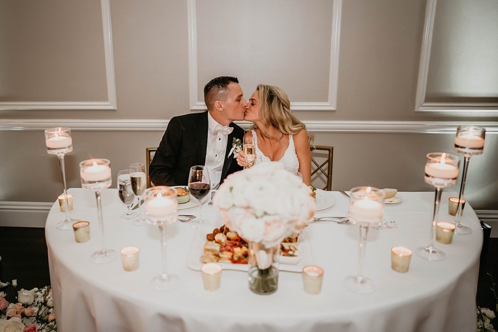 Bride and Groom kissing at sweetheart table Pelican Club Wedding Photography captured by South Florida Wedding Photographer Krystal Capone Photography