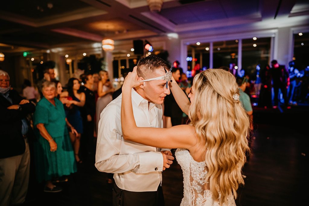 Bride putting garter on Groom's head Pelican Club Wedding Photography captured by South Florida Wedding Photographer Krystal Capone Photography