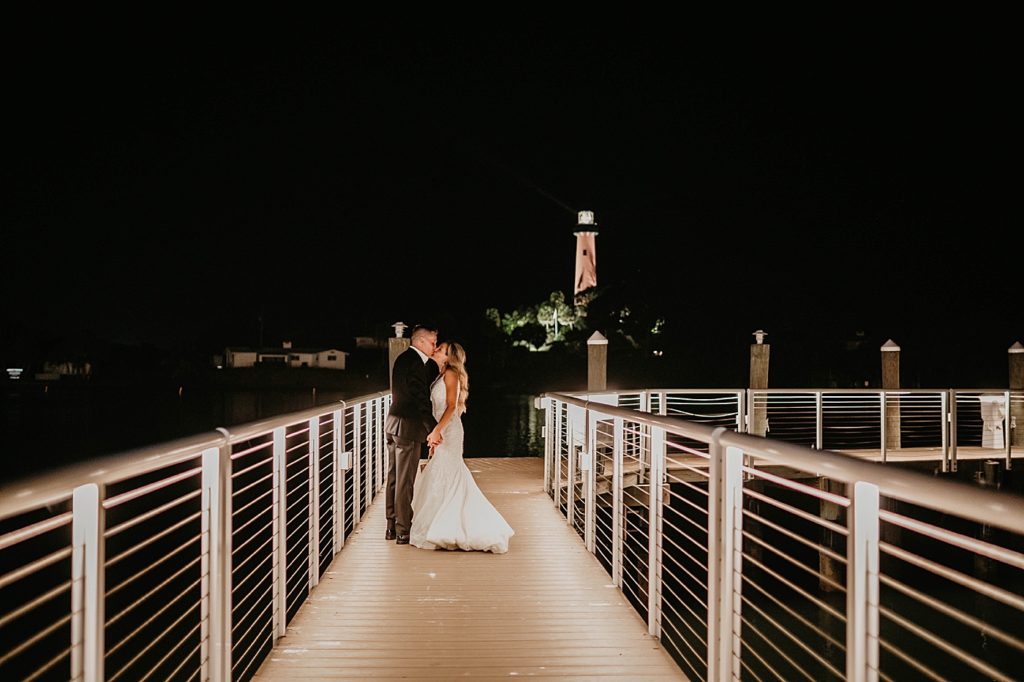 Bride and Groom kissing on the dock at night with lighthouse lot in the background Pelican Club Wedding Photography captured by South Florida Wedding Photographer Krystal Capone Photography