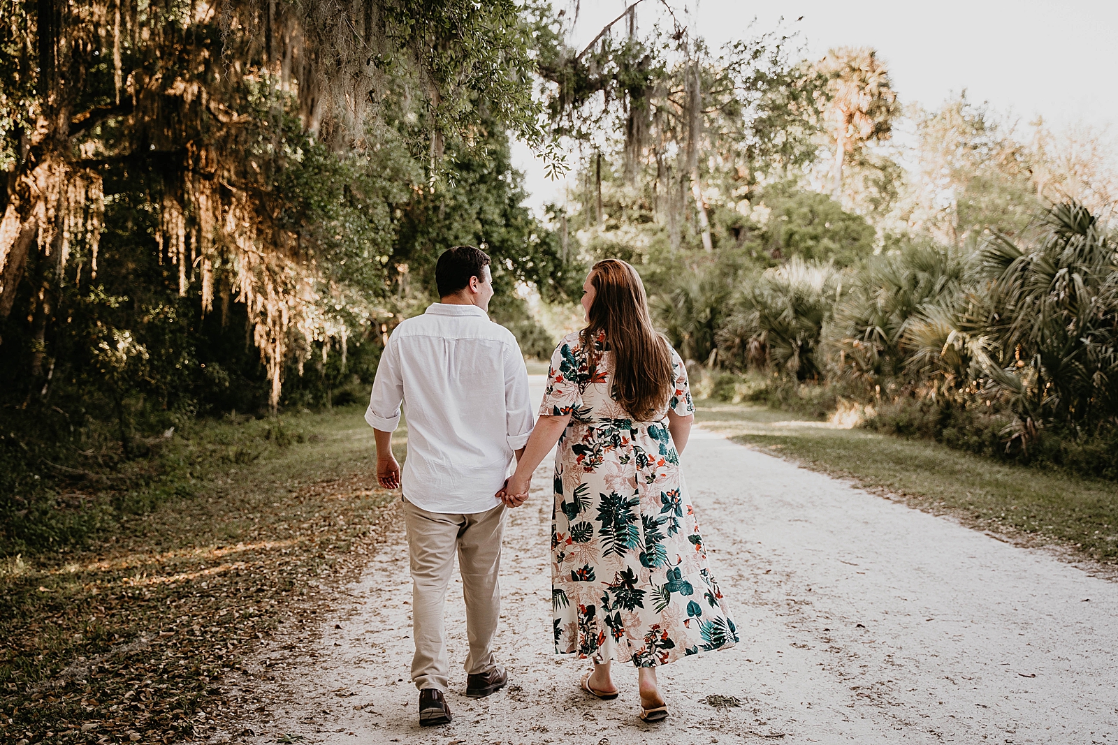 Couple holding each others hands walking on dirt path Riverbend Park Engagement Photography captured by South Florida Engagement Photographer Krystal Capone Photography 