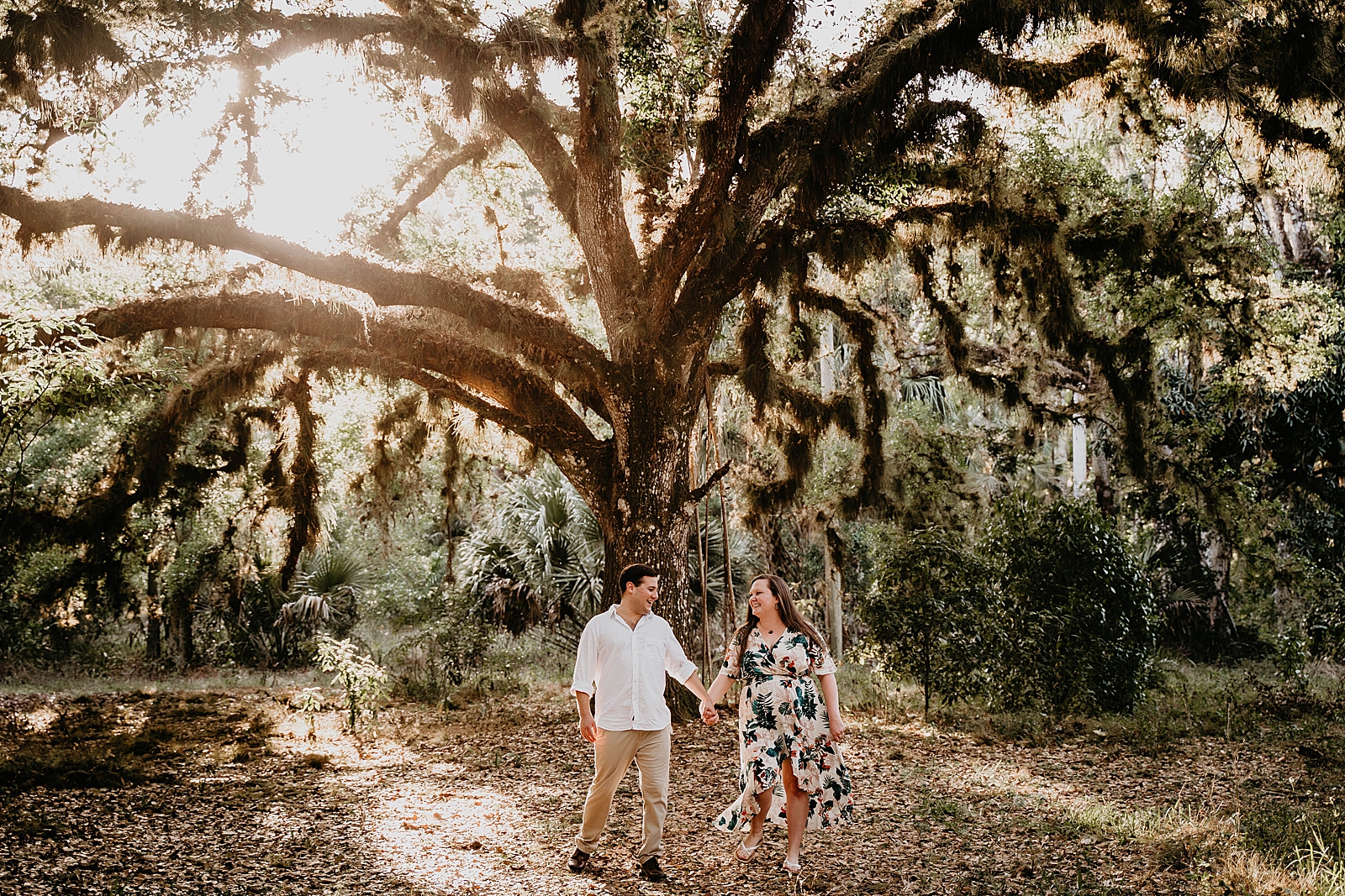 Couple holding hands in forest with autumn leafs on the ground Riverbend Park Engagement Photography captured by South Florida Engagement Photographer Krystal Capone Photography 