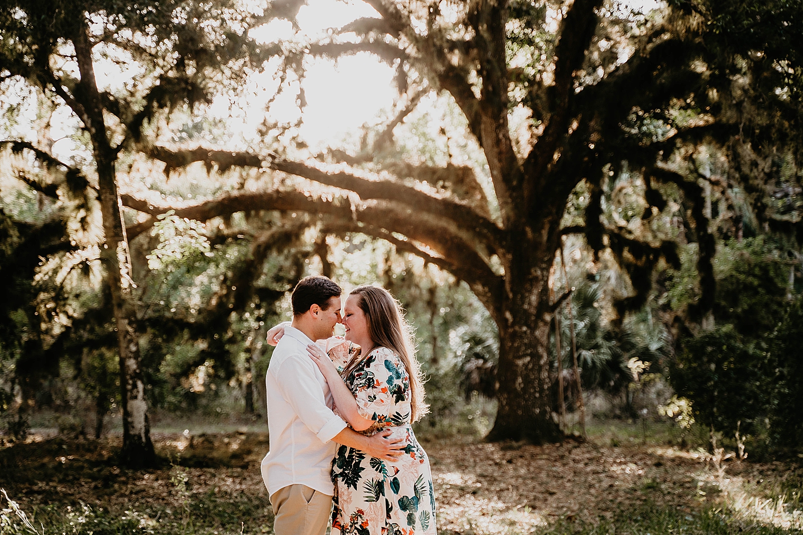 Couple nuzzling their noses with big tree behind them Riverbend Park Engagement Photography captured by South Florida Engagement Photographer Krystal Capone Photography 