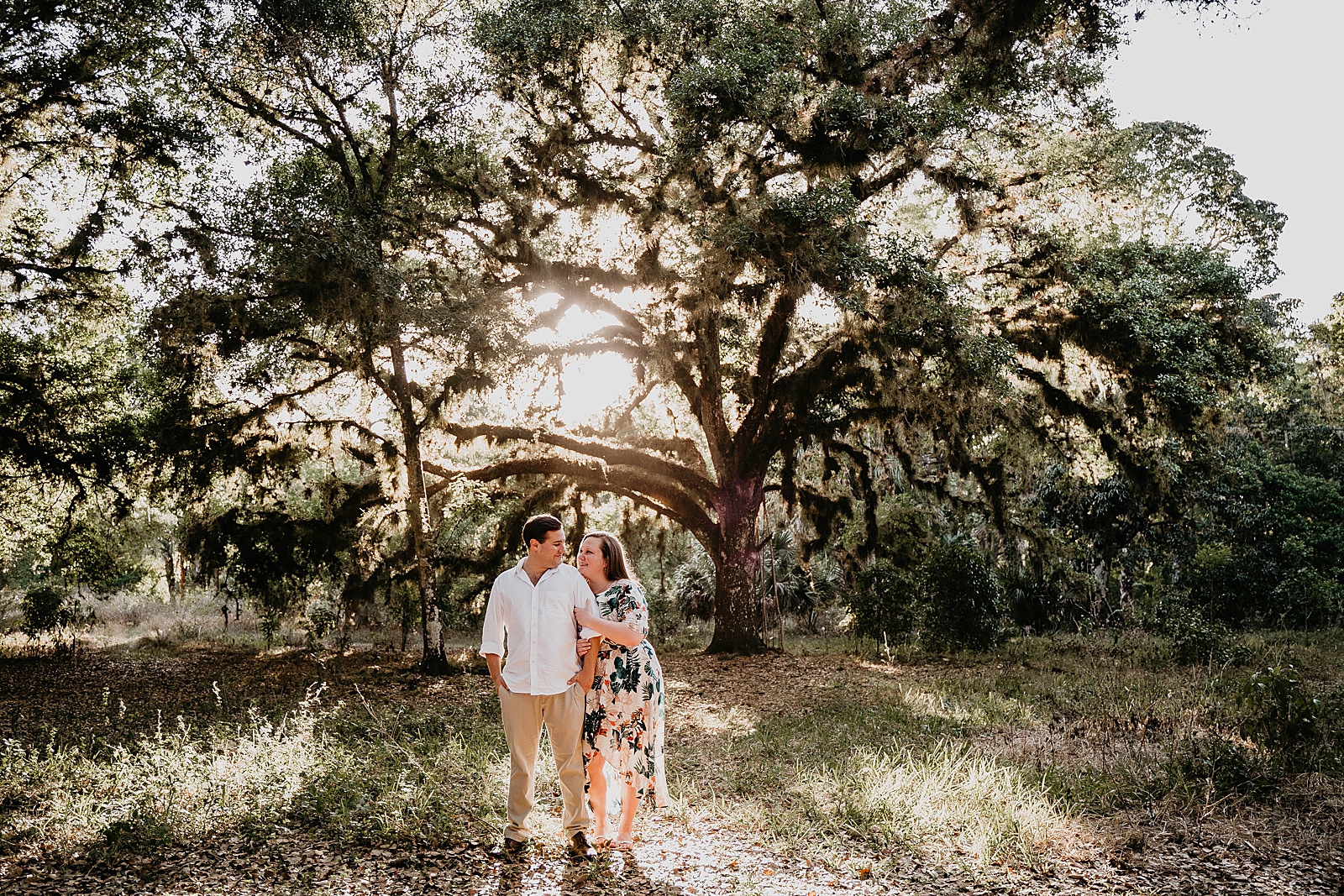 Couple holding each other in front of old Spanish moss tree in the forest Riverbend Park Engagement Photography captured by South Florida Engagement Photographer Krystal Capone Photography 