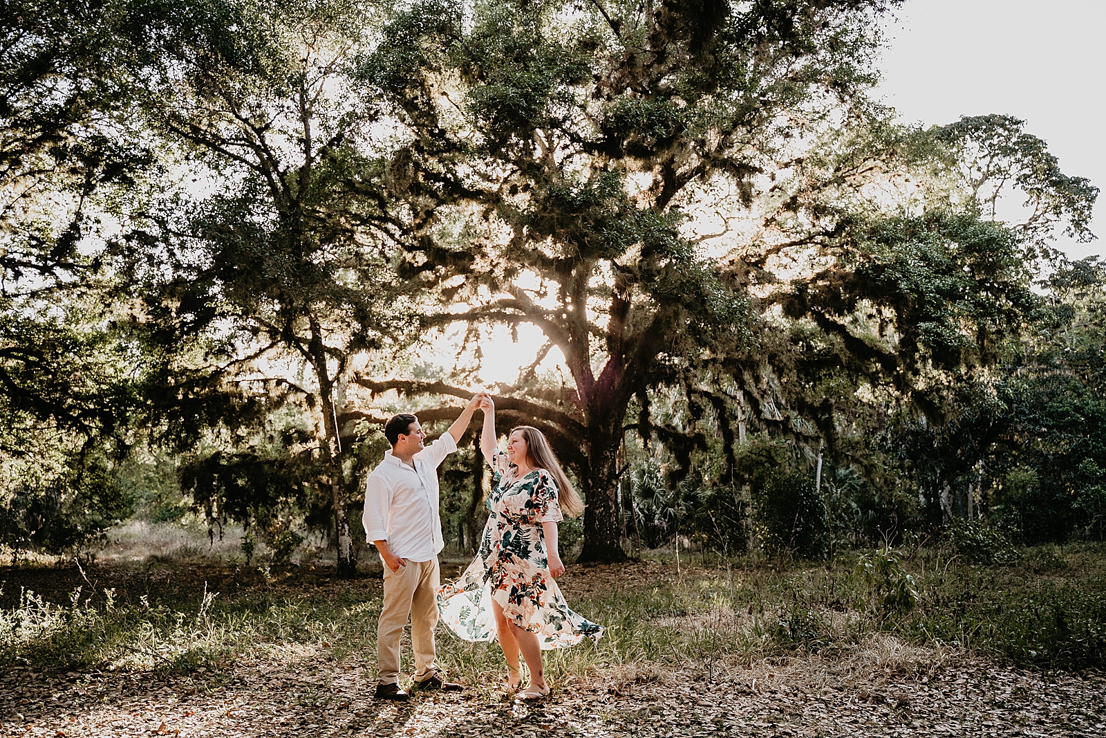 Couple pirouetting in the forest as the sun shines in Riverbend Park Engagement Photography captured by South Florida Engagement Photographer Krystal Capone Photography 