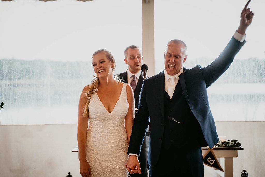 Just married Bride and Groom holding hands and Groom excited and raising his arm up in celebration The Lake House Fort Pierce Wedding Photography captured by South Florida Wedding Photographer Krystal Capone Photography 