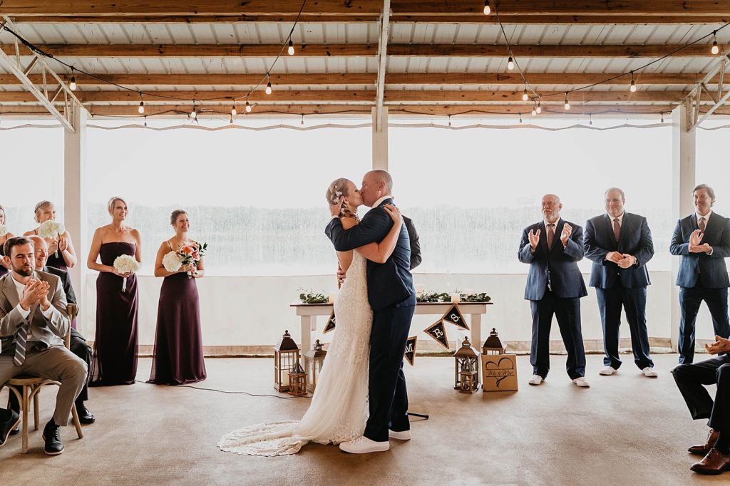 Just married Bride and Groom kissing with everyone clapping The Lake House Fort Pierce Wedding Photography captured by South Florida Wedding Photographer Krystal Capone Photography 