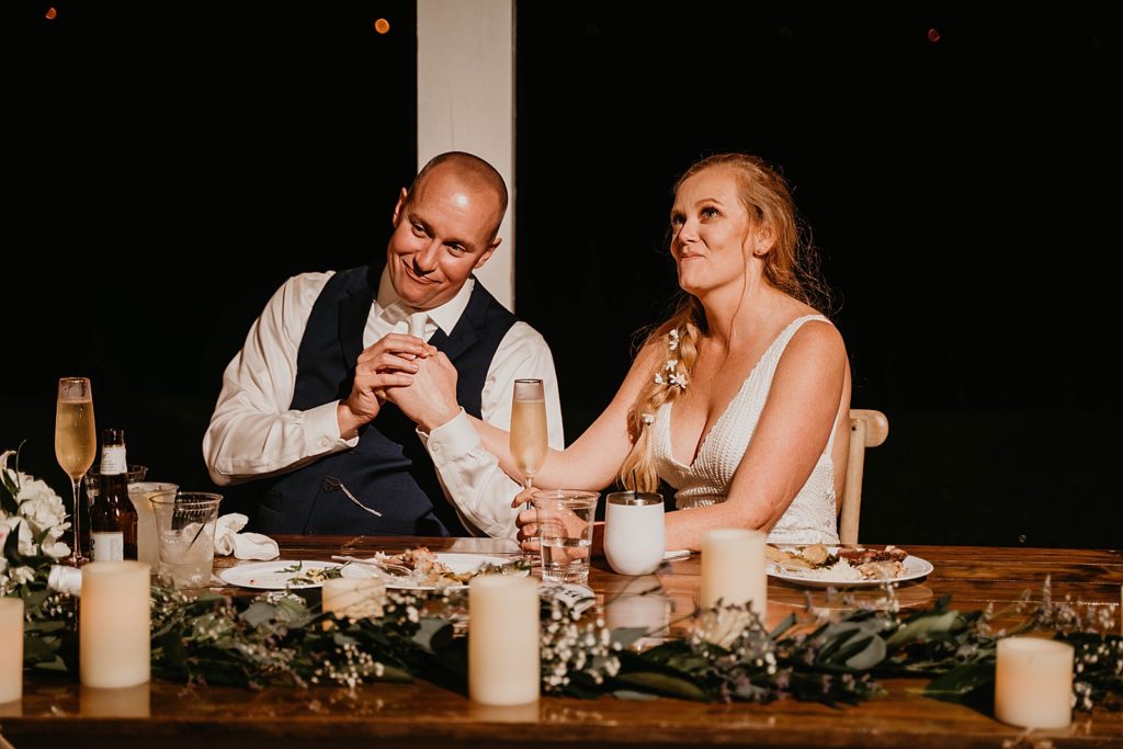 Bride and Groom holding back laughs during toast at sweetheart table The Lake House Fort Pierce Wedding Photography captured by South Florida Wedding Photographer Krystal Capone Photography 