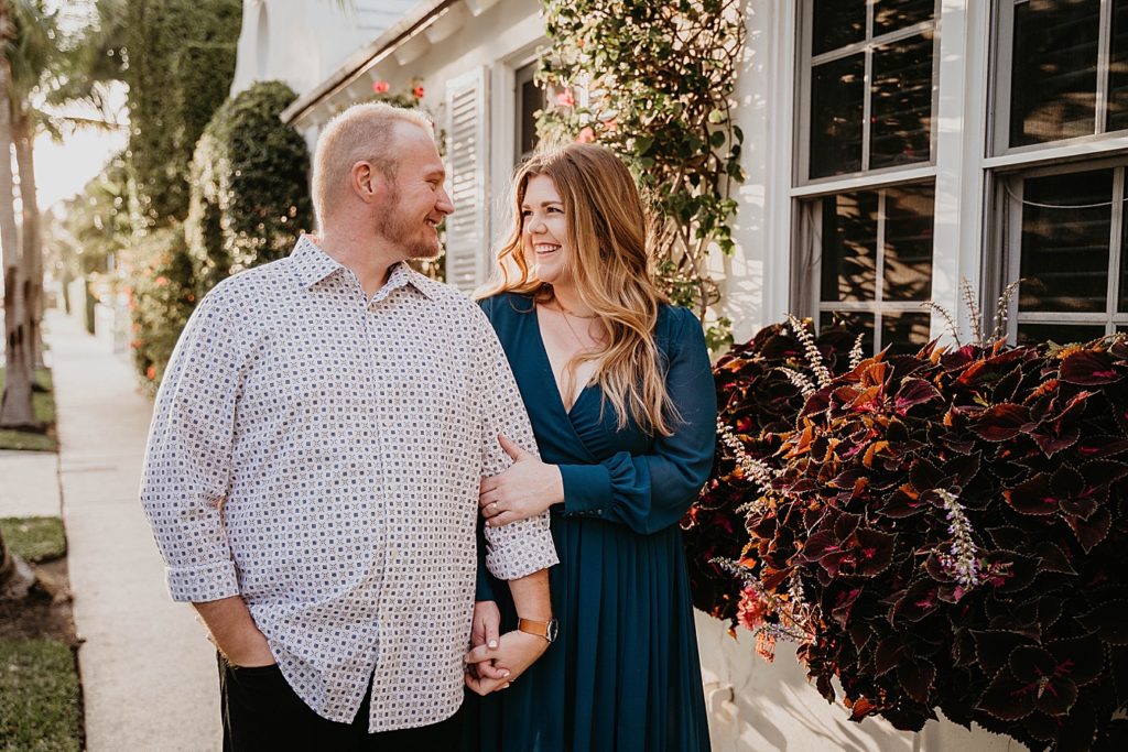 Couple holding each others hand looking at each other smiling in front of house Worth Ave Palm Beach Engagement Photography captured by South Florida Engagement Photographer Krystal Capone Photography
