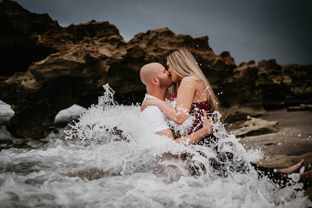 Couple kissing while the ocean water crashes into them
