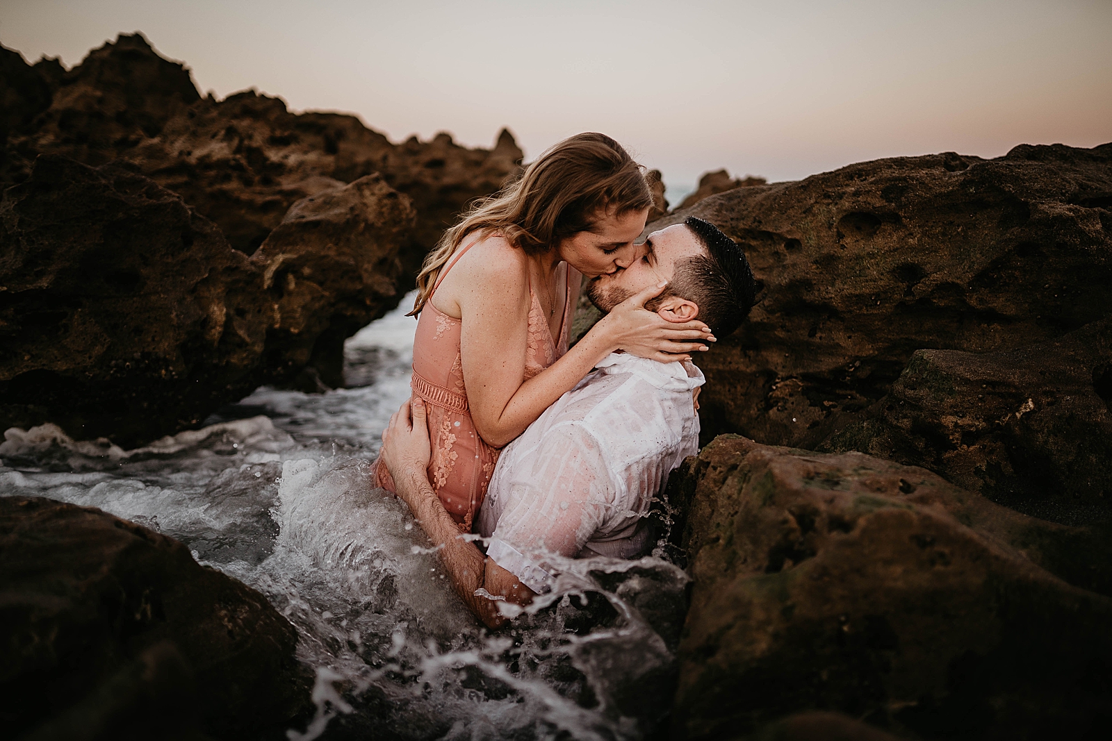 Couple kissing in the water by the beach rocks