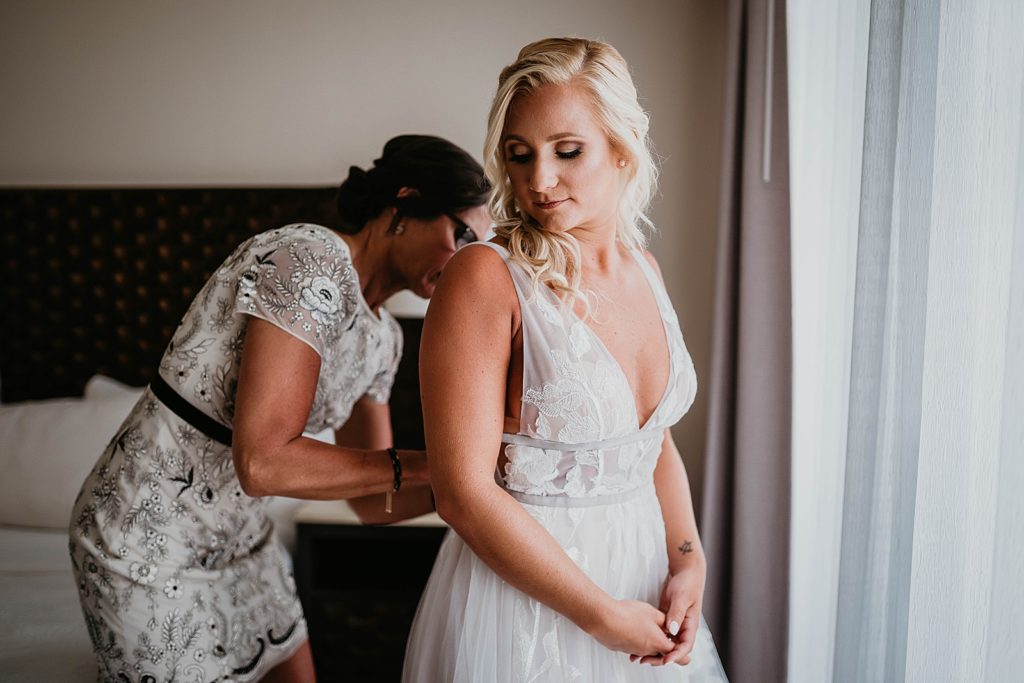 Bride getting help buttoning wedding dress