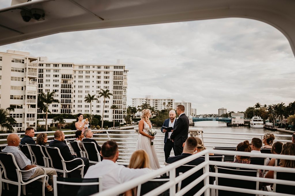 Bride and Groom on the yacht listening to officiant on the water