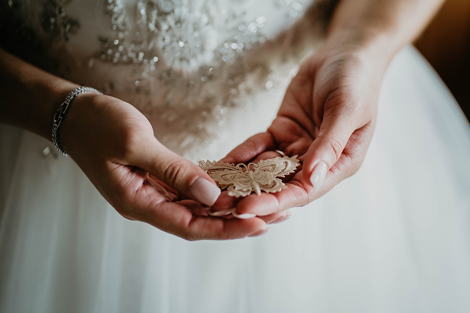 Bride holding lace butterfly in hands getting ready