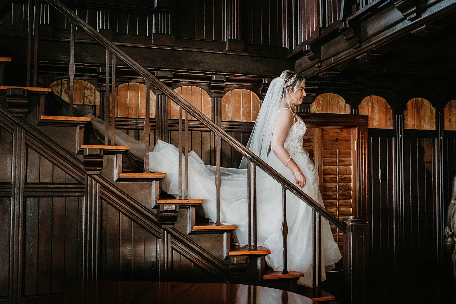 Bride in wedding dress walking down staircase