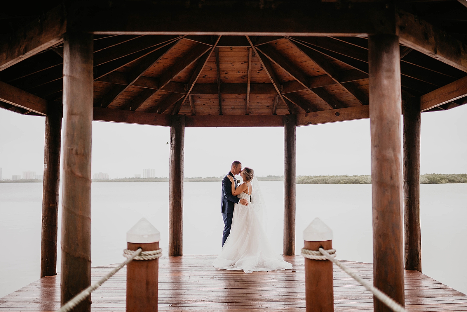 Bride and Groom holding each other and kissing on the pier