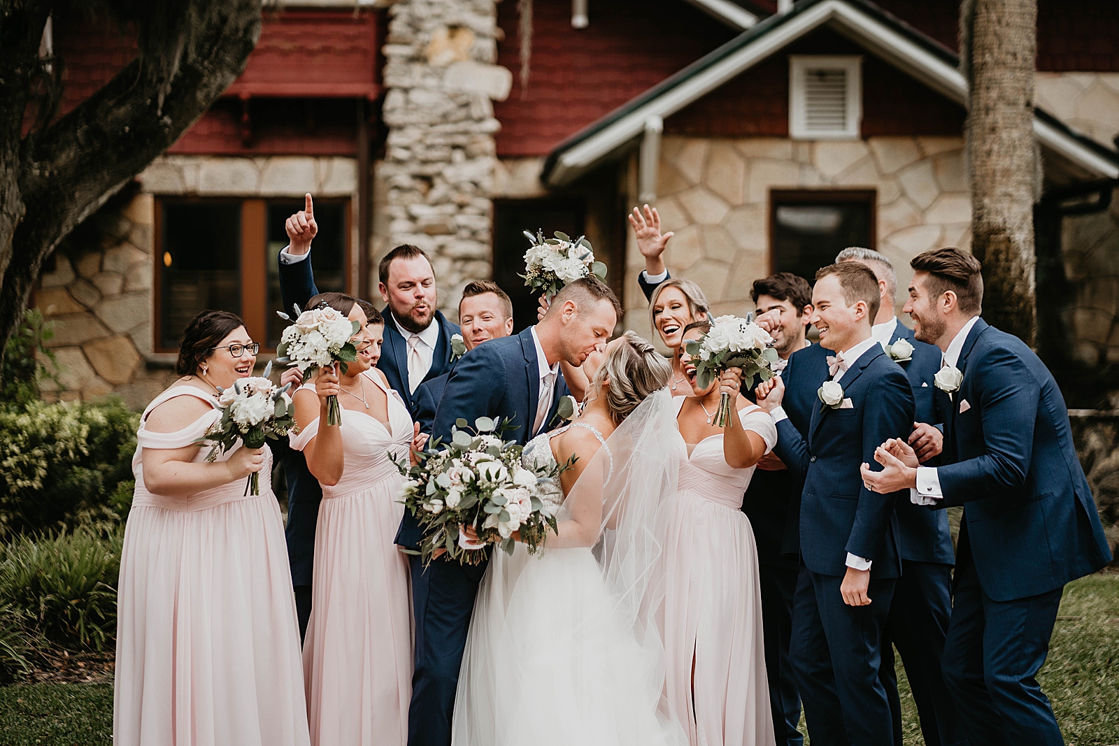 Bride and Groom kissing with wedding party reaction