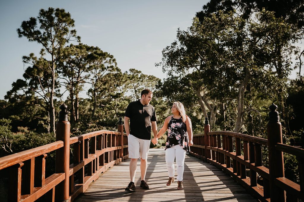 Couple holding hands crossing bridge together