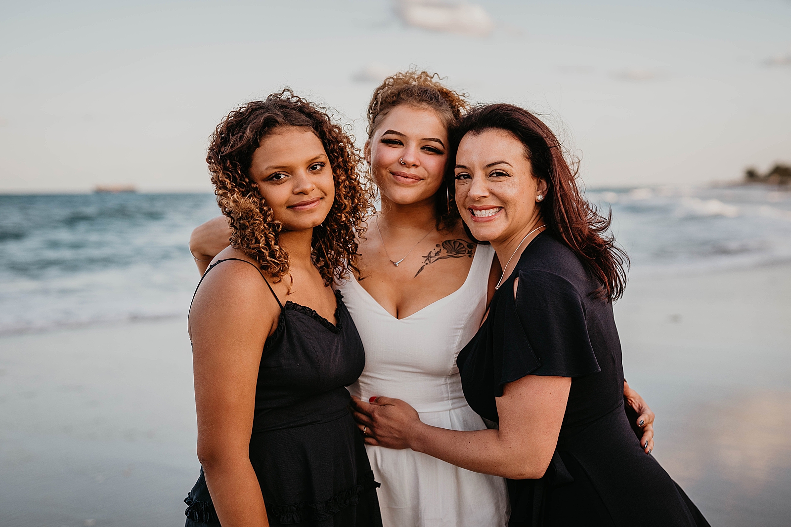 Mother hugging her daughters on the beach