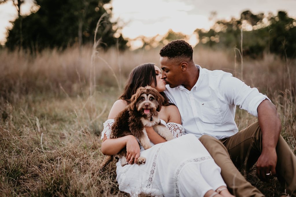 Couple sitting with dog and kissing