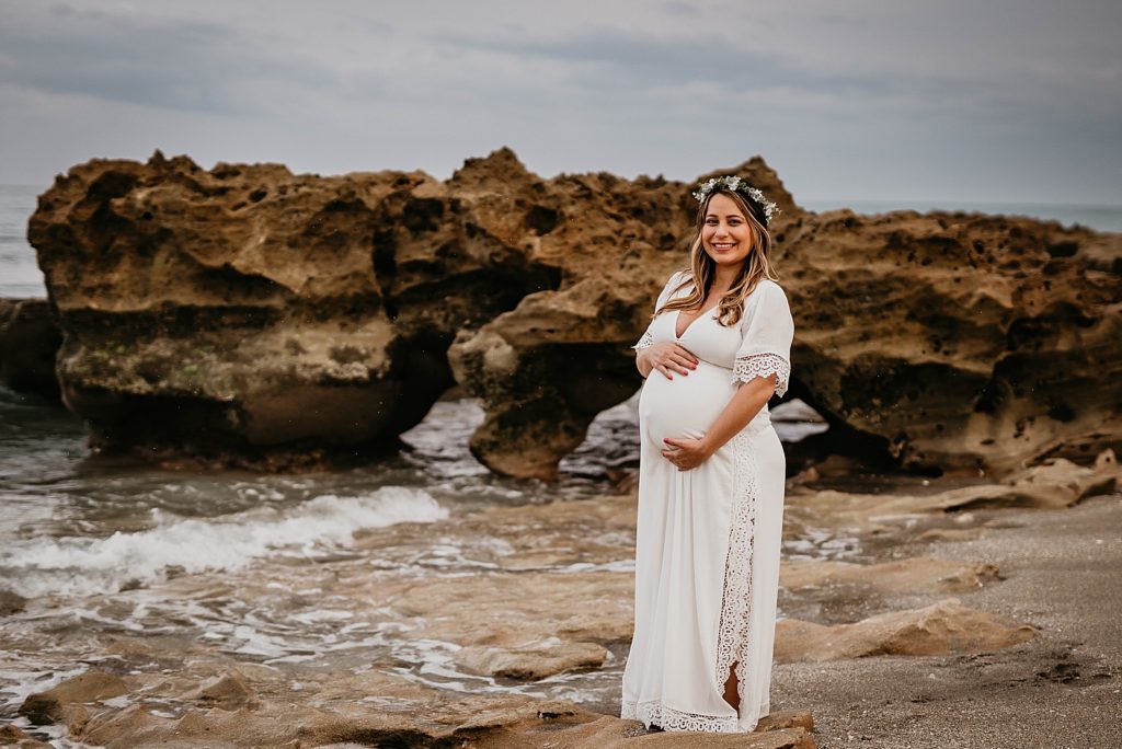 Pregnant woman standing by drift rock on the beach